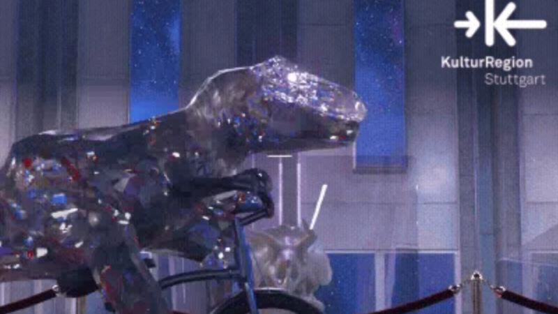 Eine glänzende Dinosaurier-Skulptur fährt auf einem Fahrrad in einer futuristischen Ausstellung. Logo der KulturRegion Stuttgart oben rechts., © Adobe Stock, flashmovie Eine glänzende Dinosaurier-Skulptur fährt auf einem Fahrrad in einer futuristischen Ausstellung. Logo der KulturRegion Stuttgart oben rechts., © Adobe Stock, flashmovie