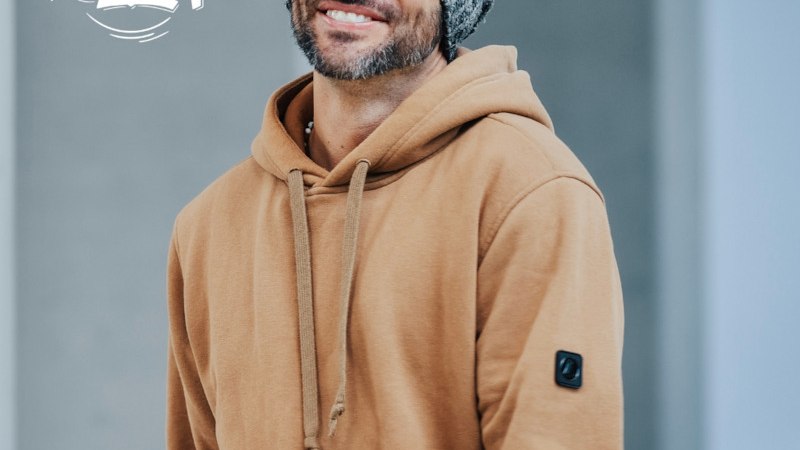 Mann mit grauer M&uuml;tze und braunem Hoodie l&auml;chelt. Schriftzug 'ESSENZ TOUR' im Vordergrund. Hintergrund unscharf., &copy; SEOM Music GmbH