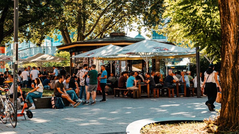 Belebter Biergarten mit vielen Menschen unter Sonnenschirmen, umgeben von Bäumen. Einige sitzen, andere stehen und unterhalten sich., © Stuttgart Marketing GmbH, Sarah Schmid Belebter Biergarten mit vielen Menschen unter Sonnenschirmen, umgeben von Bäumen. Einige sitzen, andere stehen und unterhalten sich., © Stuttgart Marketing GmbH, Sarah Schmid