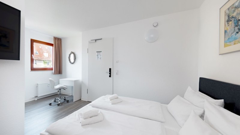 Bright double room with two beds, a desk and chair. A window with curtain and a wall mirror are visible., &copy; Hotel Olgaeck