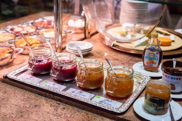 Ein Frühstücksbuffet mit verschiedenen Marmeladen, Sirup und Brotaufstrichen auf einem Tisch., © Kronen Hotel GmbH Ein Frühstücksbuffet mit verschiedenen Marmeladen, Sirup und Brotaufstrichen auf einem Tisch., © Kronen Hotel GmbH
