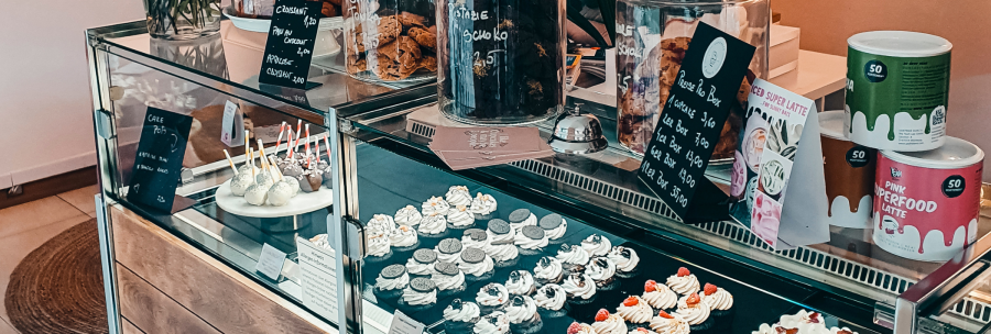 A display case in a caf&eacute; shows a selection of cupcakes, cake pops and pastries. Next to it are jars of cookies and price tags., &copy; Cupcakes & Bagels, Stuttgart