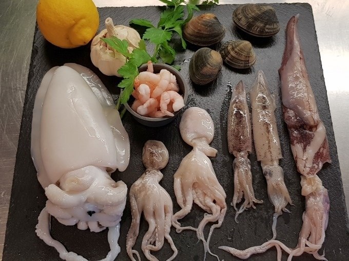 Seafood on a slate plate: squid, prawns, mussels, garlic, lemon and parsley arranged decoratively., &copy; Kultweine-Kochwelten-Kunst&uuml;cke - Kochschule Sonja Lenz
