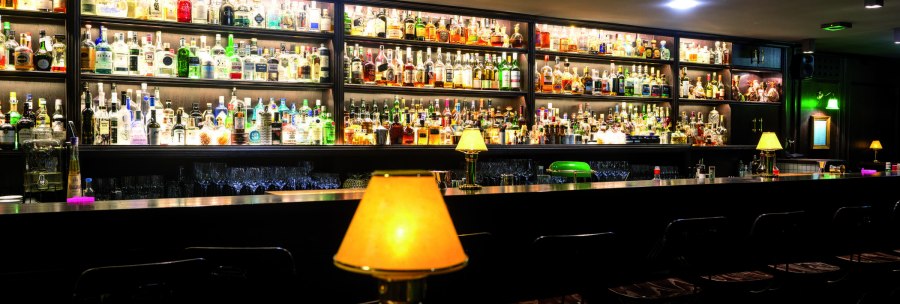 A stylish bar with numerous bottles on shelves and warmly lit lamps on the counter., &copy; TMBW, Gregor Lengler