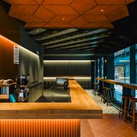 Modern bar with wooden counter, stools and stylish lighting in the Shobu Calwer Passage. Dark walls and geometric ceiling patterns., © Blackbook Studios Modern bar with wooden counter, stools and stylish lighting in the Shobu Calwer Passage. Dark walls and geometric ceiling patterns., © Blackbook Studios