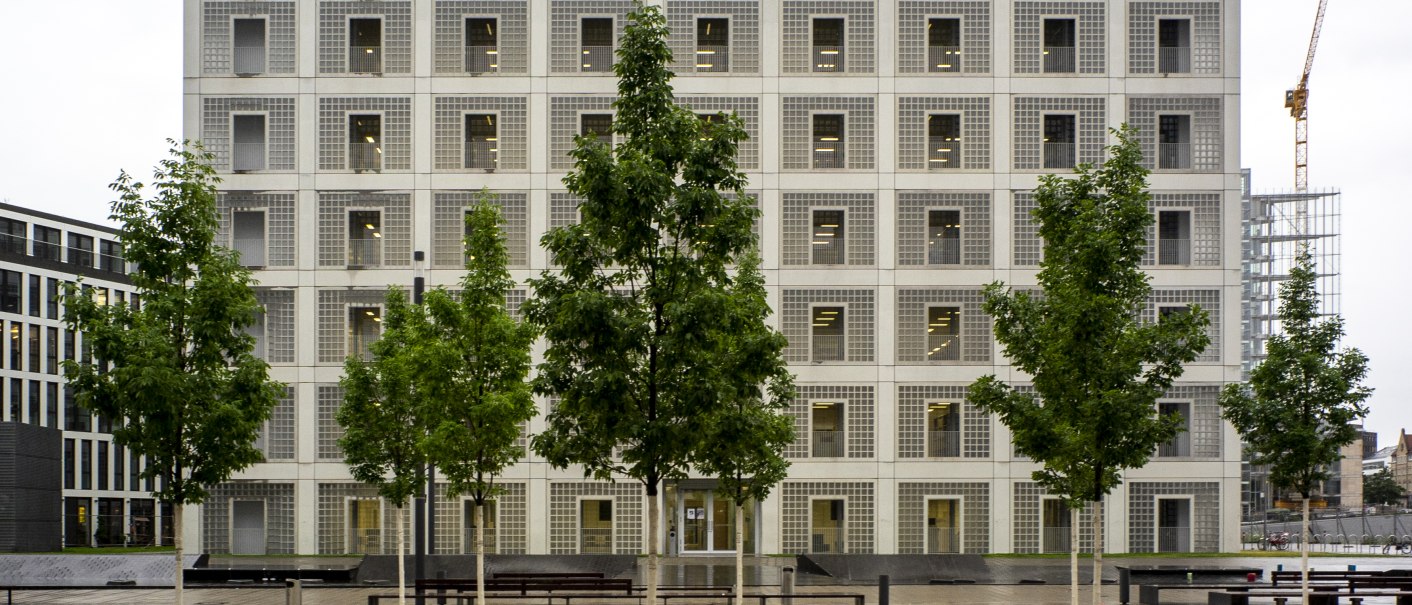 Die Stadtbibliothek Stuttgart mit ihrer symmetrischen, modernen Fassade und Bäumen im Vordergrund an einem bewölkten Tag., © Frank Hoerner Die Stadtbibliothek Stuttgart mit ihrer symmetrischen, modernen Fassade und Bäumen im Vordergrund an einem bewölkten Tag., © Frank Hoerner