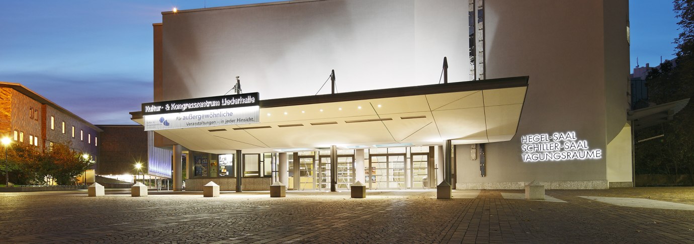 Eingang der Liederhalle Stuttgart bei D&auml;mmerung, beleuchtet mit Schildern f&uuml;r Hegel-Saal, Schiller-Saal und Tagungsr&auml;ume., &copy; Kultur- und Kongresszentrum Liederhalle