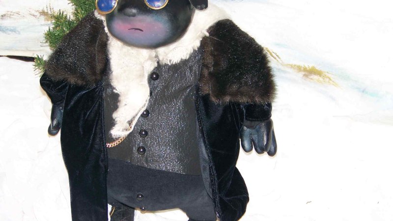 Eine Maulwurf-Figur tr&auml;gt elegante Kleidung und eine Sonnenbrille, steht vor einem schneebedeckten Hintergrund mit Tannen. Stilvoll und winterlich gekleidet., &copy; Nellys Puppentheater