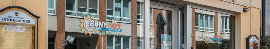 Eingang des Restaurants 'Ebony' mit Schildern f&uuml;r afrikanische K&uuml;che. Fenster spiegeln die gegen&uuml;berliegende Stra&szlig;e wider. Seit 1987 ge&ouml;ffnet., &copy; SMG, Sarah Schmid