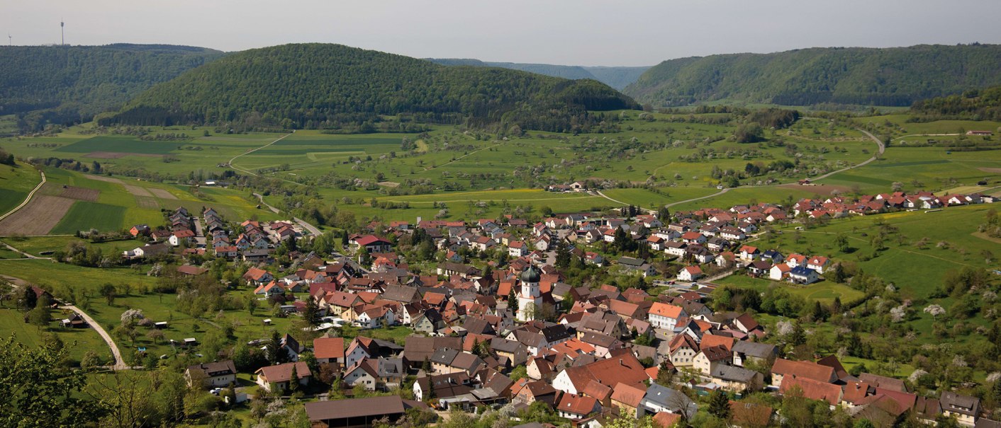Aerial view of Bad Überkingen, surrounded by green hills and fields. The town shows red and brown roofs, embedded in a rural landscape., © © Stuttgart-Marketing GmbH