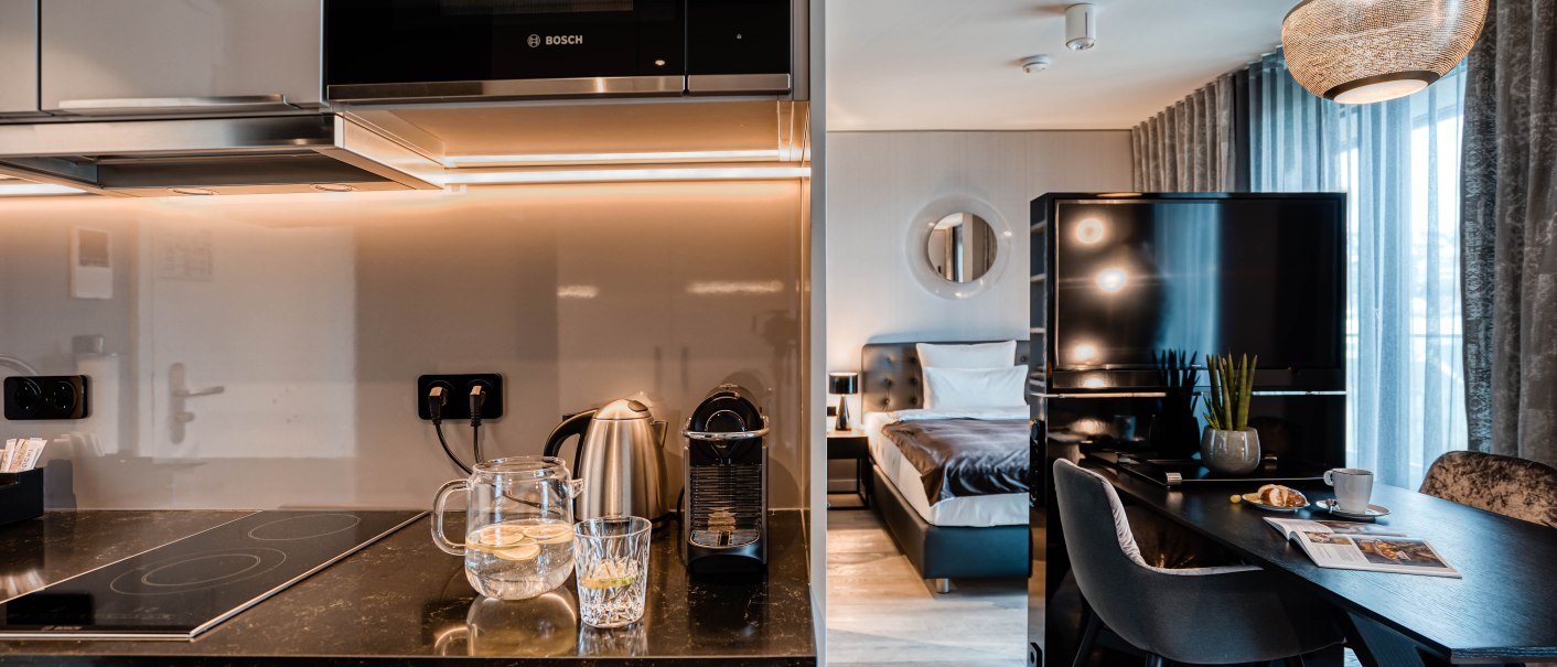 Moderne Suite mit Küchenzeile, Esstisch und Bett. Helle Beleuchtung, stilvolle Einrichtung und große Fenster mit Vorhängen., © CLOUD N°7 APARTMENTS GmbH Moderne Suite mit Küchenzeile, Esstisch und Bett. Helle Beleuchtung, stilvolle Einrichtung und große Fenster mit Vorhängen., © CLOUD N°7 APARTMENTS GmbH