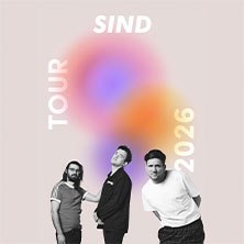Drei Männer posieren vor einem verschwommenen, bunten Hintergrund. Der Text 'SIND TOUR 2026' ist in Weiß geschrieben., © links im Bild Drei Männer posieren vor einem verschwommenen, bunten Hintergrund. Der Text 'SIND TOUR 2026' ist in Weiß geschrieben., © links im Bild