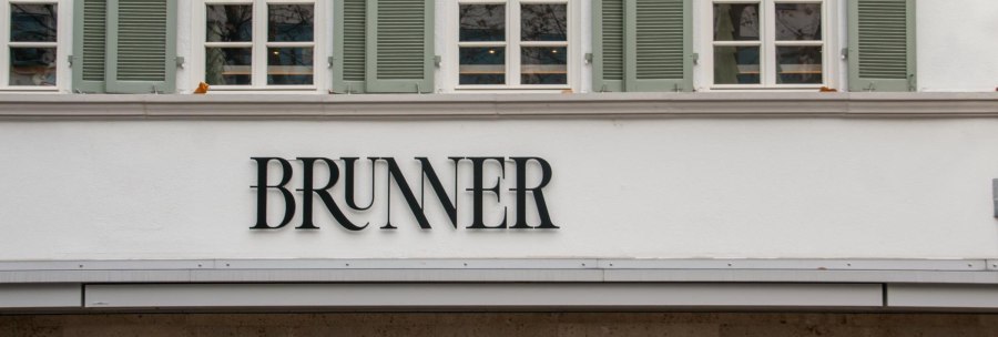 Lettering on the facade of the Brunner restaurant with serifs. Above it, lattice windows with green shutters., &copy; SMG, Sarah Schmid