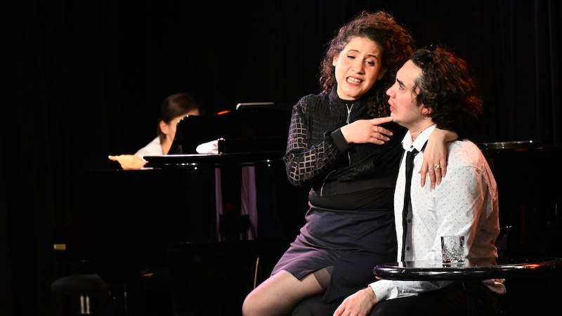 Eine Frau singt leidenschaftlich auf einer Bühne, während ein Mann neben ihr sitzt. Im Hintergrund ist ein Klavier zu sehen., © Internationale Hugo-Wolf-Akademie Eine Frau singt leidenschaftlich auf einer Bühne, während ein Mann neben ihr sitzt. Im Hintergrund ist ein Klavier zu sehen., © Internationale Hugo-Wolf-Akademie