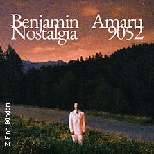 Ein Mann in weißem Anzug steht auf einer Wiese vor einem Wald bei Sonnenuntergang. Oben ist der Text 'Benjamin Amaru - Nostalgia 9052' zu sehen., © links im Bild Ein Mann in weißem Anzug steht auf einer Wiese vor einem Wald bei Sonnenuntergang. Oben ist der Text 'Benjamin Amaru - Nostalgia 9052' zu sehen., © links im Bild