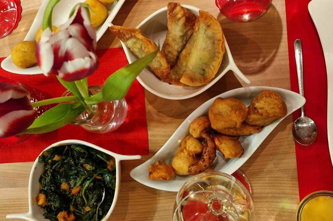 Ein Tisch mit indischen Vorspeisen wie Samosas und frittiertem Gemüse, dekoriert mit Tulpen und Getränken. Einladende Atmosphäre für einen Kochkurs., © Kultweine-Kochwelten-Kunstücke - Kochschule Sonja Lenz Ein Tisch mit indischen Vorspeisen wie Samosas und frittiertem Gemüse, dekoriert mit Tulpen und Getränken. Einladende Atmosphäre für einen Kochkurs., © Kultweine-Kochwelten-Kunstücke - Kochschule Sonja Lenz