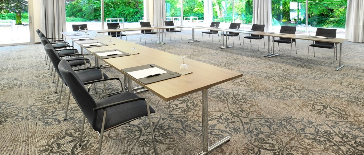 Modern conference room with long tables, chairs and large windows overlooking a green landscape., © Schlosshotel Monrepos Modern conference room with long tables, chairs and large windows overlooking a green landscape., © Schlosshotel Monrepos