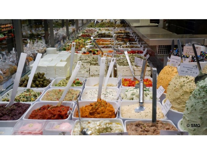 Vielfältige Auswahl an Oliven, Käse und Aufstrichen in einer Markthalle, präsentiert in weißen Behältern mit Schaufeln., © Stuttgart Marketing GmbH Vielfältige Auswahl an Oliven, Käse und Aufstrichen in einer Markthalle, präsentiert in weißen Behältern mit Schaufeln., © Stuttgart Marketing GmbH
