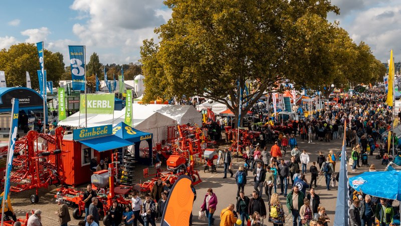 Eine belebte Messe mit zahlreichen Besuchern, Ständen und landwirtschaftlichen Maschinen. Bunte Fahnen und Zelte prägen das Bild., © Daniel Schneider, 2022 Eine belebte Messe mit zahlreichen Besuchern, Ständen und landwirtschaftlichen Maschinen. Bunte Fahnen und Zelte prägen das Bild., © Daniel Schneider, 2022