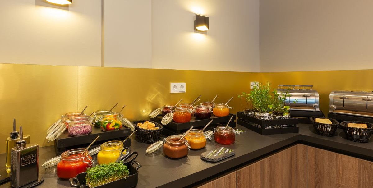 A breakfast buffet with a variety of jams, fresh herbs, and toasters set up on a counter., &copy; Novum Hospitality