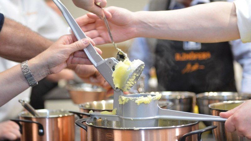 Several people use a potato ricer to press potatoes into a pot. More pots can be seen in the background., © Ilzhöfer, Stuttgart Several people use a potato ricer to press potatoes into a pot. More pots can be seen in the background., © Ilzhöfer, Stuttgart