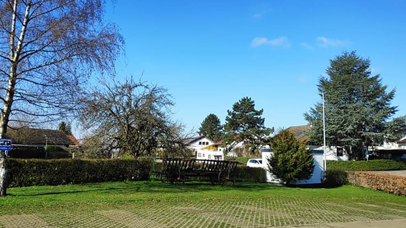 Ein Wohnmobilstellplatz mit Bäumen und einem Parkplatzschild. Im Hintergrund sind Häuser und ein blauer Himmel zu sehen., © Dieter Schurr, Gasthaus Hirsch