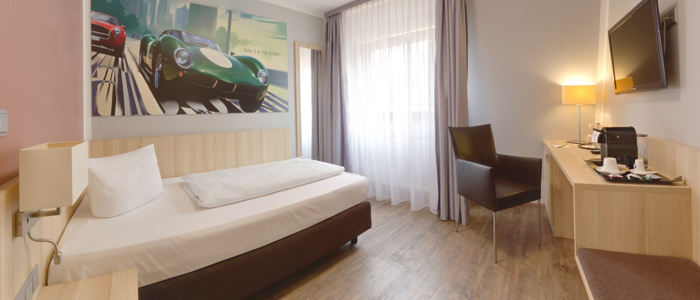 Modernes Einzelzimmer mit Bett, Schreibtisch, Stuhl und großem Wandbild von Autos. Helle Vorhänge und Holzfußboden schaffen eine einladende Atmosphäre., © attimo Hotel Stuttgart Modernes Einzelzimmer mit Bett, Schreibtisch, Stuhl und großem Wandbild von Autos. Helle Vorhänge und Holzfußboden schaffen eine einladende Atmosphäre., © attimo Hotel Stuttgart