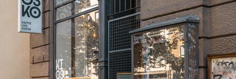 Ein Kiosk mit der Aufschrift 'Kiosko Kaffee und Kiosk'. Die Fassade ist mit Graffiti bedeckt, und das Schaufenster spiegelt die Umgebung wider., &copy; SMG, Sarah Schmid