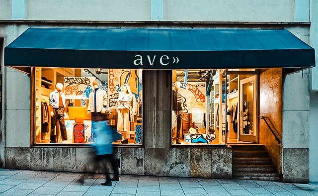 Schaufenster eines Modegeschäfts mit Graffiti-Dekoration. Eine Person geht vorbei. Der Laden trägt den Namen 'ave'., © Mario P. Rodrigues Schaufenster eines Modegeschäfts mit Graffiti-Dekoration. Eine Person geht vorbei. Der Laden trägt den Namen 'ave'., © Mario P. Rodrigues