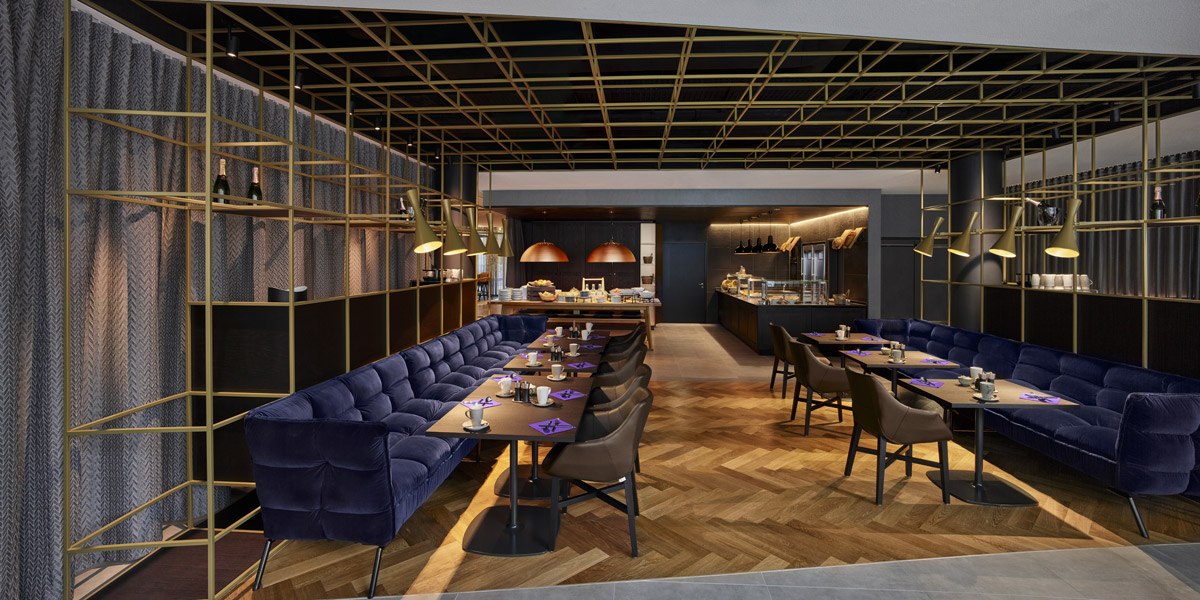 Elegant restaurant with blue sofas, wooden floor and golden lamps. Open kitchen in the background, stylish atmosphere., © Jaz Hotel Stuttgart Elegant restaurant with blue sofas, wooden floor and golden lamps. Open kitchen in the background, stylish atmosphere., © Jaz Hotel Stuttgart