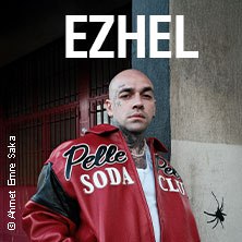 Person in roter Jacke mit 'Pelle Soda Club' Schriftzug, steht vor einem Gebäude. Oben steht 'EZHEL'. © Ahmet Emre Saka., © links im Bild Person in roter Jacke mit 'Pelle Soda Club' Schriftzug, steht vor einem Gebäude. Oben steht 'EZHEL'. © Ahmet Emre Saka., © links im Bild