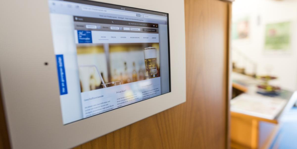 Ein Bildschirm in einer Holzwand zeigt eine Webseite mit einem Bild von Getränken. Der Hintergrund ist unscharf., © ARNOTEL GmbH Ein Bildschirm in einer Holzwand zeigt eine Webseite mit einem Bild von Getränken. Der Hintergrund ist unscharf., © ARNOTEL GmbH