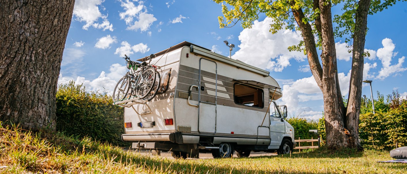 Ein Wohnmobil mit Fahrrädern am Heck steht auf einem grünen Stellplatz unter Bäumen. Der Himmel ist blau mit weißen Wolken., © Stuttgart-Marketing GmbH, Thomas Niedermüller Ein Wohnmobil mit Fahrrädern am Heck steht auf einem grünen Stellplatz unter Bäumen. Der Himmel ist blau mit weißen Wolken., © Stuttgart-Marketing GmbH, Thomas Niedermüller