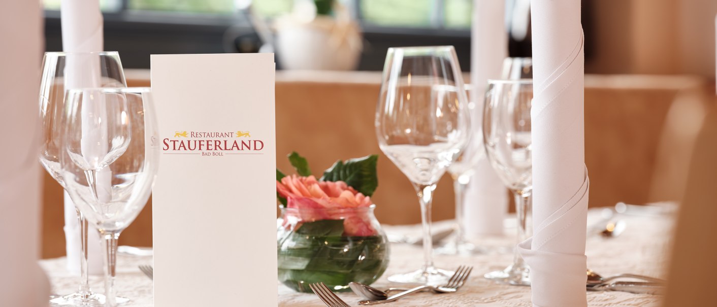 Eleganter Tisch im Restaurant Stauferland mit Weingläsern, weißen Servietten und einer Blumendekoration in einem Glasgefäß., © Badhotel Restaurant Stauferland