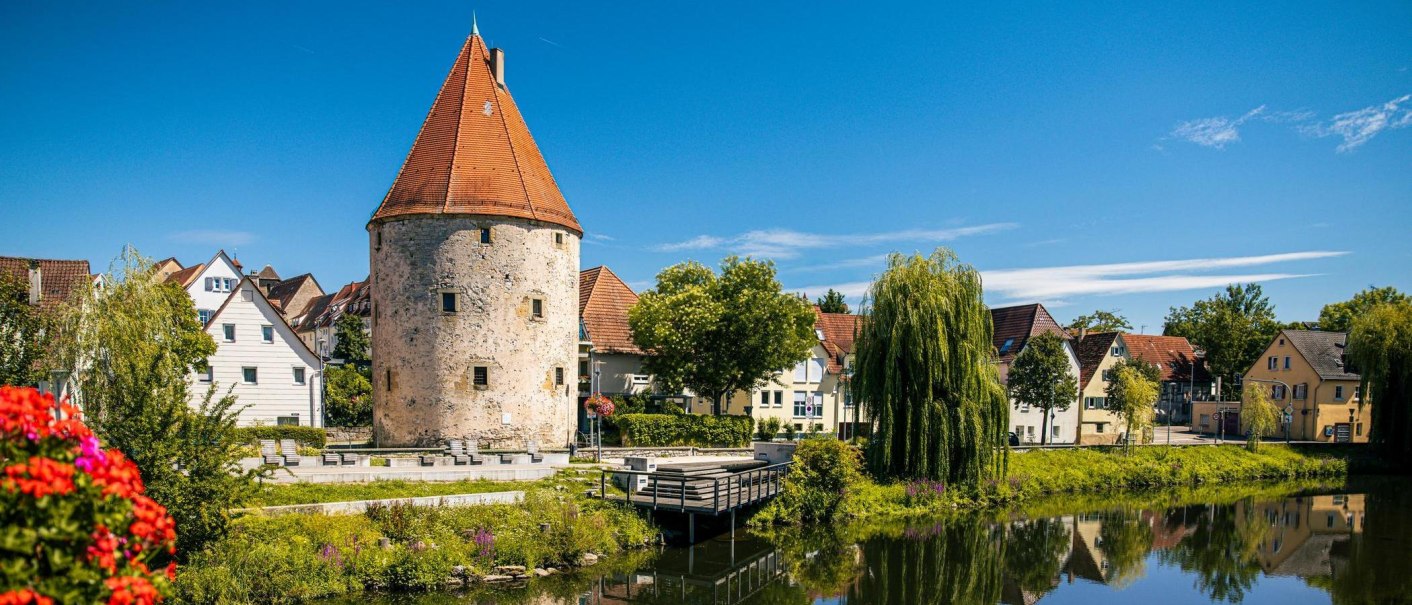 The historic Powder Tower in Vaihingen an der Enz, surrounded by picturesque houses and a tranquil river under a blue sky., © SMG Stuttgart Marketing GmbH - Sarah Schmid The historic Powder Tower in Vaihingen an der Enz, surrounded by picturesque houses and a tranquil river under a blue sky., © SMG Stuttgart Marketing GmbH - Sarah Schmid