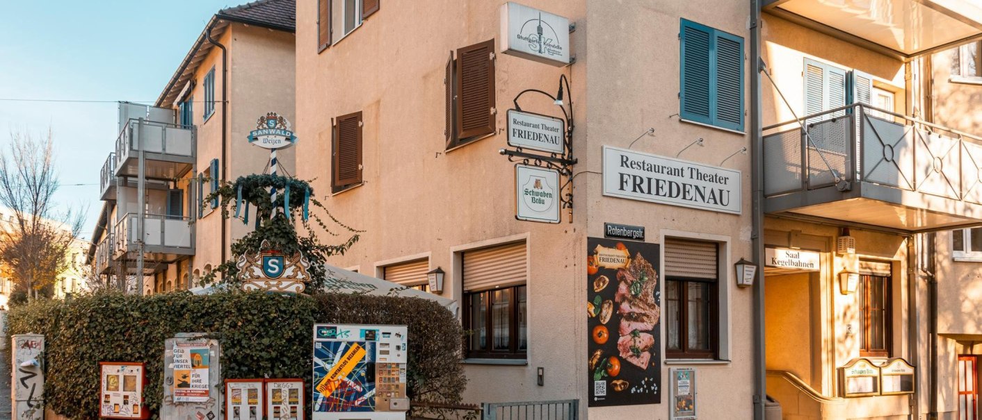 Das Restaurant Theater Friedenau zeigt seine Fassade mit mehreren Schildern und einem Werbeplakat. Ein Biergarten ist ebenfalls sichtbar., &copy; Stuttgart-Marketing GmbH, Sarah Schmid
