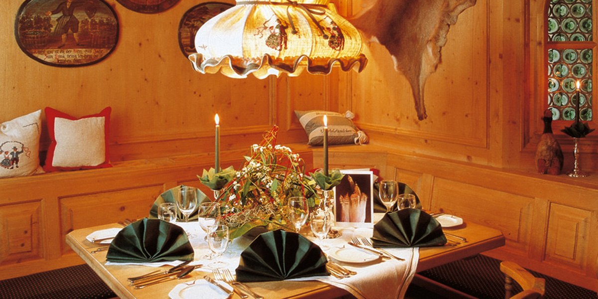 A rustic table setting in a restaurant with wooden paneling, candles and green napkins. A cozy atmosphere with traditional decor., © © H-Hotels.com A rustic table setting in a restaurant with wooden paneling, candles and green napkins. A cozy atmosphere with traditional decor., © © H-Hotels.com