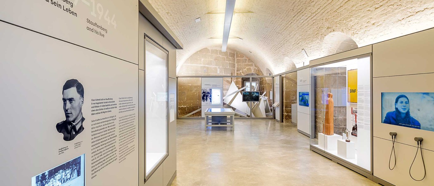 Innenansicht der Stauffenberg-Erinnerungsstätte mit modernen Ausstellungsstücken, Informationstafeln und Bildschirmen in einem gewölbten Raum., © Haus der Geschichte Baden-Württemberg