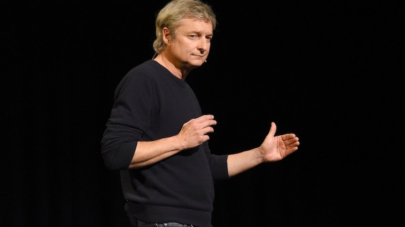 Person in schwarzem Pullover gestikuliert auf einer Bühne vor schwarzem Hintergrund., © Theaterhaus Stuttgart e.V. Person in schwarzem Pullover gestikuliert auf einer Bühne vor schwarzem Hintergrund., © Theaterhaus Stuttgart e.V.