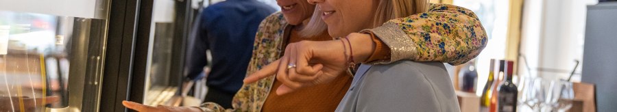 Zwei Frauen stehen vor einem Weinspender und zeigen auf verschiedene Weinflaschen. Im Hintergrund sind weitere Flaschen und Gläser zu sehen., © Stuttgart Marketing GmbH, Fotografin Martina Denker Zwei Frauen stehen vor einem Weinspender und zeigen auf verschiedene Weinflaschen. Im Hintergrund sind weitere Flaschen und Gläser zu sehen., © Stuttgart Marketing GmbH, Fotografin Martina Denker