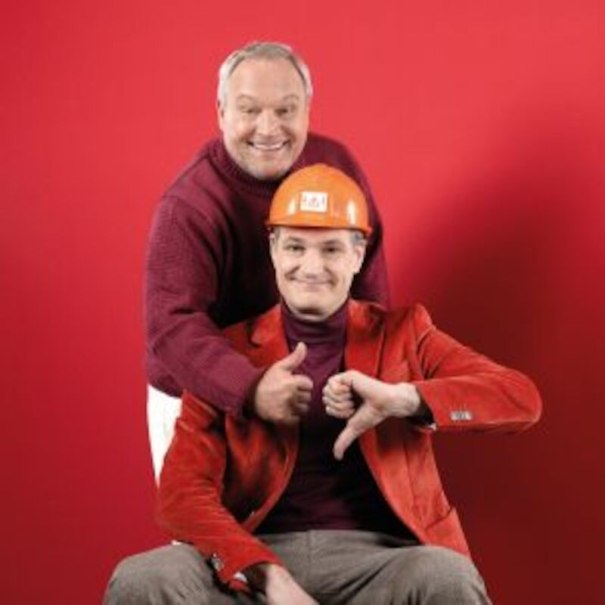 Two men in front of a red background. One is wearing a construction helmet and giving a thumbs-up, the other a thumbs-down. Both are smiling., &copy; Altes Schauspielhaus und Kom&ouml;die im Marquardt e.V.