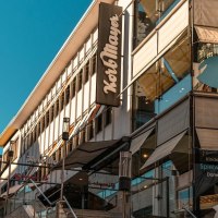 Gebäude mit Korbmayer-Schild, Schaufenster mit Kinderkleidung und Spielwaren. Moderne Architektur unter blauem Himmel., © Stuttgart Marketing GmbH, Sarah Schmid Gebäude mit Korbmayer-Schild, Schaufenster mit Kinderkleidung und Spielwaren. Moderne Architektur unter blauem Himmel., © Stuttgart Marketing GmbH, Sarah Schmid