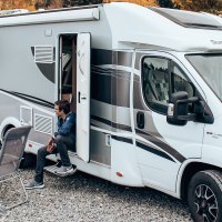 Ein Wohnmobil steht auf einem Stellplatz. Drei Personen sitzen davor an einem Tisch, ein Hund ist ebenfalls zu sehen. Herbstliche Bäume im Hintergrund., © Erlebnisregion Schwäbischer Albtrauf e.V.