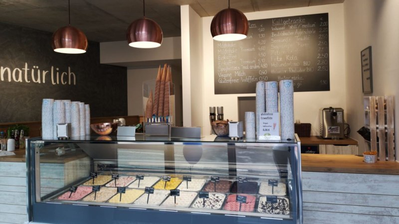 Ice cream parlor with ice cream counter, various types of ice cream, menu board and modern lighting. 'Naturally' lettering on the wall., &copy; Joannis Nakos