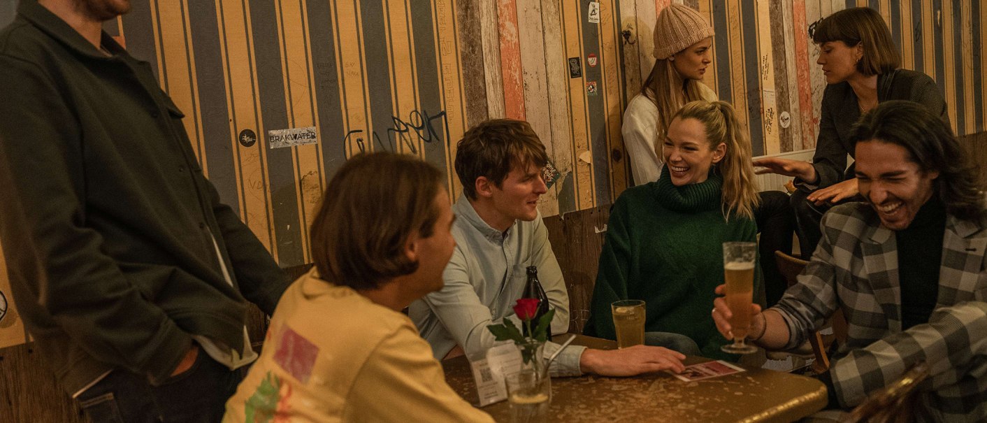A group of people are sitting in a cozy bar and laughing. They are enjoying drinks and having a lively conversation. The room has a warm atmosphere., © © Stuttgart-Marketing GmbH, Martina Denker