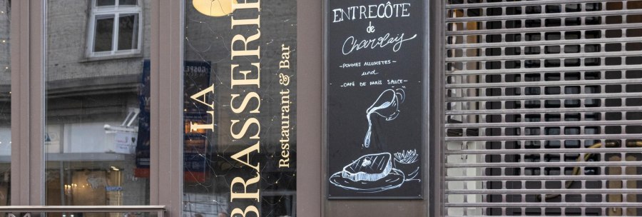 Entrance of 'La Brasserie' with menu board offering entrec&ocirc;te de Charolais with fries and Caf&eacute; de Paris sauce., &copy; SMG, Sarah Schmid