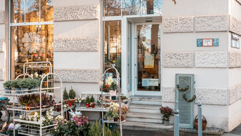A flower store with plants and decorations in front of the entrance. A bicycle is parked next to it., © SMG Stuttgart Marketing GmbH - Sarah Schmid A flower store with plants and decorations in front of the entrance. A bicycle is parked next to it., © SMG Stuttgart Marketing GmbH - Sarah Schmid