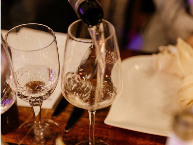 Ein Glas wird mit Wein gefüllt, daneben stehen weitere Gläser und Besteck auf einem gedeckten Tisch., © Cool-Tours StattReisen Ein Glas wird mit Wein gefüllt, daneben stehen weitere Gläser und Besteck auf einem gedeckten Tisch., © Cool-Tours StattReisen