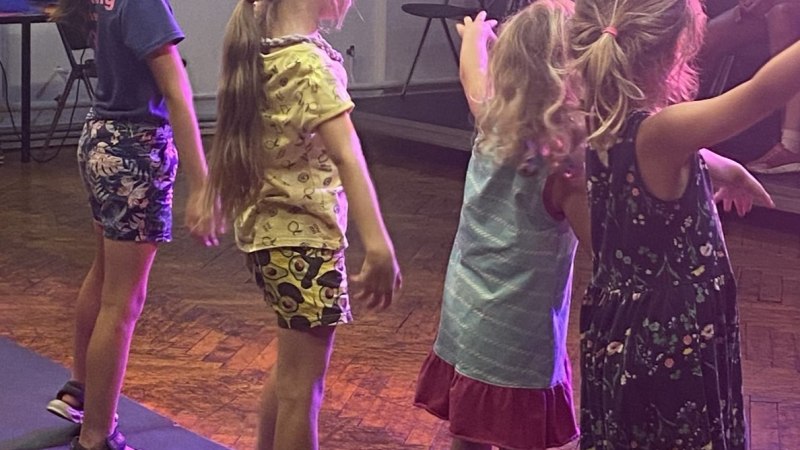 Fünf Kinder tanzen in einem Raum mit Holzboden. Sie tragen Sommerkleidung und scheinen eine Choreografie zu üben., © Tathea - Lena Oschowitzer Fünf Kinder tanzen in einem Raum mit Holzboden. Sie tragen Sommerkleidung und scheinen eine Choreografie zu üben., © Tathea - Lena Oschowitzer