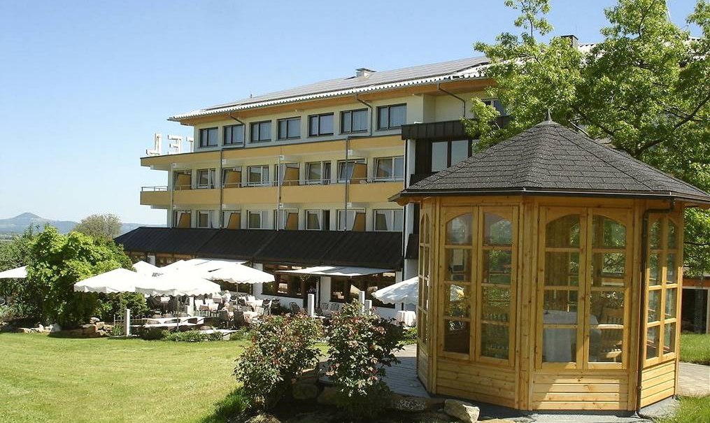 Das Badhotel Restaurant Stauferland mit gelber Fassade, Terrasse mit Sonnenschirmen und einem hölzernen Pavillon im Garten., © Badhotel Restaurant Stauferland